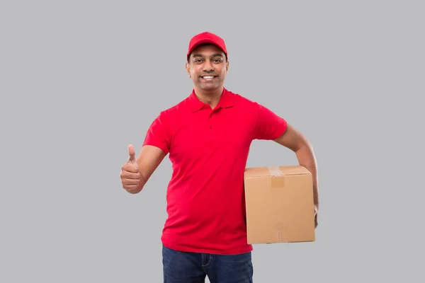 Delivery Man Holding Box Hands Εμφανίζοντας Thumb Απομονωμένο Κόκκινο Μπλουζάκι — Φωτογραφία Αρχείου