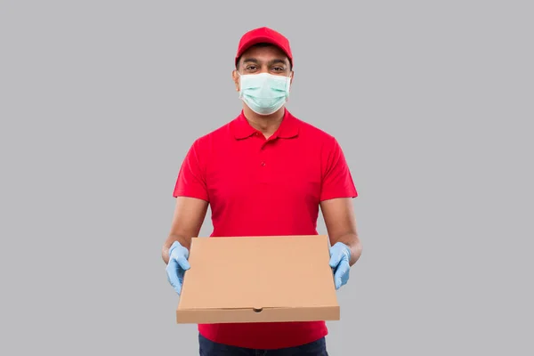 Delivery Man Pizza Box in Hands Wearing Medical Mask and Gloves Isolated. Red Tshirt Indian Delivery Boy. Delivery