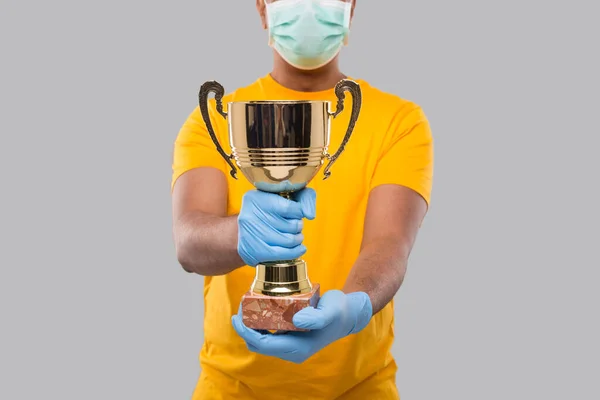 Índio homem segurando troféu no mãos vestindo médico máscara e luvas close up isolado — Fotografia de Stock