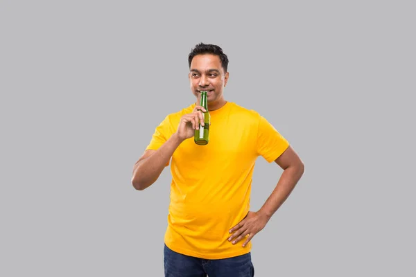 Uomo indiano che beve birra dalla bottiglia di birra isolato. — Foto Stock