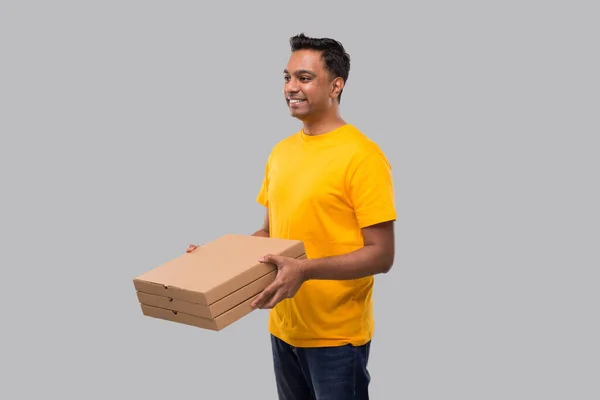 Mann drei Pizzaschachteln in der Hand beobachtet Seite isoliert. Gelbes T-Shirt indischer Lieferjunge. Mann mit Pizza in der Hand — Stockfoto