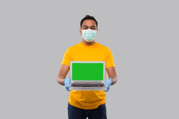 Delivery Man Visar Laptop Grön skärm bär medicinsk mask och handskar. Hembeställningar, Karantänleverans, Shopping Online, Frilansare koncept. — Stockfoto