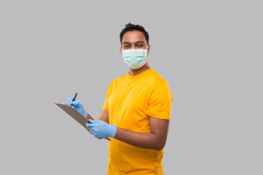 Hintli adam panoya yazı yazıyor. Tıbbi maske takıyor ve kamerada eldiven takıyor. Hintli adam Panosu