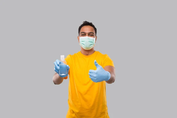 Indiano homem mostrando mãos desinfetante e polegar para cima vestindo máscara médica e luvas isoladas. Indiano homem segurando mão anti-séptico — Fotografia de Stock