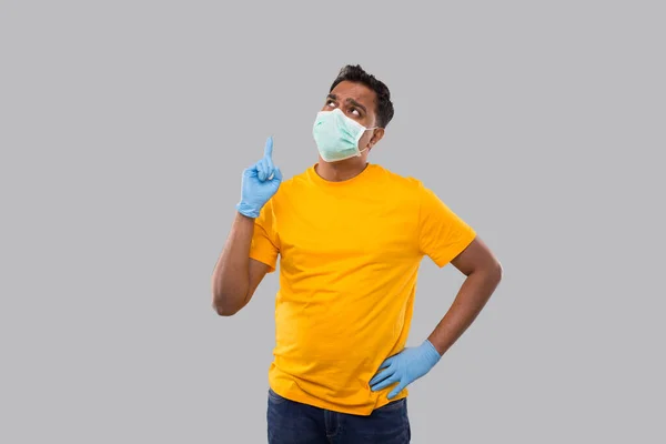 Indiase man wijst omhoog dragen van medische masker en handschoenen geïsoleerd. De mens denkend — Stockfoto