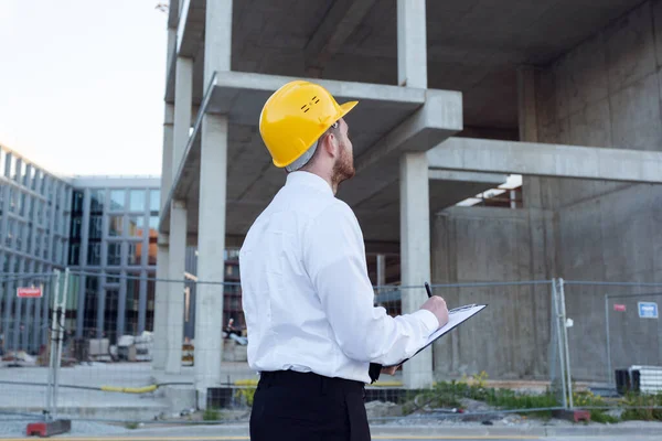 Man Controlling Building. Builder making marks in Clipboard. House Building. Businessman