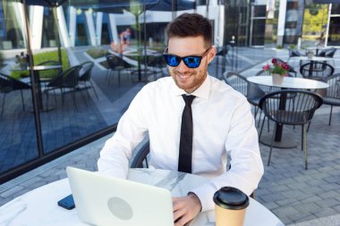 Terrace 'ın dışındaki dizüstü bilgisayarda çalışan bir iş adamı. Güneşli bir günde restoranda güneş gözlüğü takan bir iş adamı. Bağımsız İş
