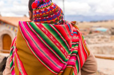 Chinchero, Peru - Ekim 05, 2018: Geleneksel renkli giysiler giymiş yerli kadın bebeği sırtında olarak yerel markette yürüyor