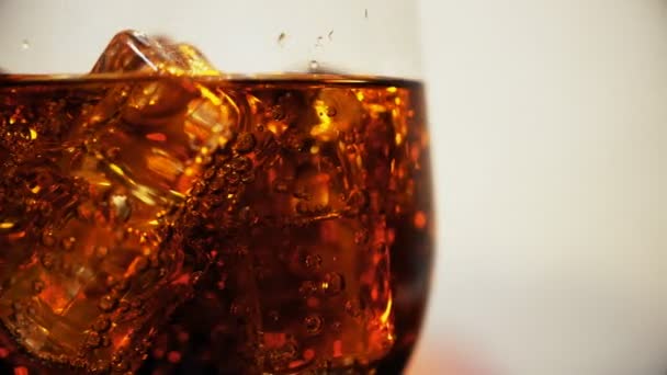 Cola im Glas mit Eiswürfeln und Blasen, die rotieren. Lebensmittel-Hintergrund. Natron aus nächster Nähe. — Stockvideo