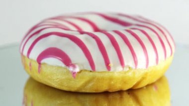 Rotating donuts with different fillings on the mirror table. Delicious sweet donut rotating on a plate. Bright and colorful donut close-up macro shot spinning on a white background. Seamless loop.