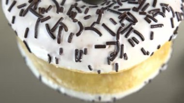 Rotating donuts with different fillings on the mirror table. Delicious sweet donut rotating on a plate. Bright and colorful donut close-up macro shot spinning on a white background. Seamless loop.