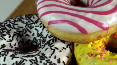 Rotating donuts with different fillings on the mirror table. Delicious sweet donut rotating on a plate. Bright and colorful donut close-up macro shot spinning on a white background. Seamless loop.