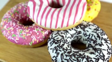 Masada farklı dolgular ile donuts dönen. Lezzetli tatlı donut bir tabakta dönen. Parlak ve renkli donut yakın çekim makro beyaz bir arka plan üzerinde dönen vurdu. Sorunsuz döngü.