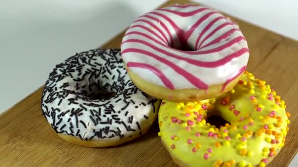 Donuts rotativos com diferentes recheios na mesa. Delicioso donut doce girando em um prato. Donut brilhante e colorido close-up macro tiro girando em um fundo branco. loop sem costura . — Vídeo de Stock