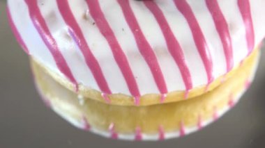 Rotating donuts with different fillings on the mirror table. Delicious sweet donut rotating on a plate. Bright and colorful donut close-up macro shot spinning on a white background. Seamless loop.