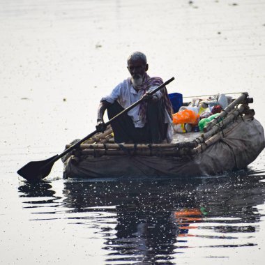 Yeni Delhi, Hindistan - Mart 04, 2020: Bir adam sabah saatlerinde Hindistan 'ın New Deli kentindeki Yamuna Nehri ghatında bir sandalda kürek çekiyor