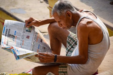 Yeni Delhi, Hindistan - Mart 04, 2020: Sabah saatlerinde Hindistan, Yamuna Ghat View 'deki Yamuna Nehri ghat' ında Hint gazetesi okuyan bir adam