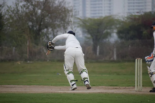 Full length of cricketer playing on field during sunny day, Cricketer on the field in action, Players playing cricket match at field during the day time