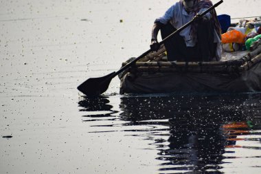 Yeni Delhi, Hindistan - Mart 04, 2020: Bir adam sabah saatlerinde Hindistan 'ın New Deli kentindeki Yamuna Nehri ghatında bir sandalda kürek çekiyor