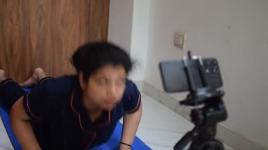 Evde yoga yapan genç Hintli bir kadın çevrimiçi yoga seansında güzel bir kız temel yoga pozisyonunda Asyalı bir kadın kapalı alanda yoga yapıyor. 