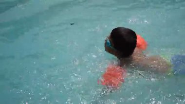 Havuzda yüzen mutlu Hintli çocuk, sıcak yaz tatillerinde hava tüpüyle birlikte yüzen çocuk, büyük bir havuzda yüzen çocuk..