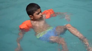 Havuzda yüzen mutlu Hintli çocuk, sıcak yaz tatillerinde hava tüpüyle birlikte yüzen çocuk, büyük bir havuzda yüzen çocuk..