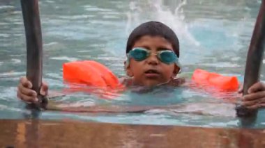 Havuzda yüzen mutlu Hintli çocuk, sıcak yaz tatillerinde hava tüpüyle birlikte yüzen çocuk, büyük bir havuzda yüzen çocuk..