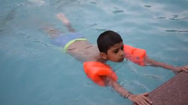 Havuzda yüzen mutlu Hintli çocuk, sıcak yaz tatillerinde hava tüpüyle birlikte yüzen çocuk, büyük bir havuzda yüzen çocuk..