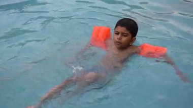 Havuzda yüzen mutlu Hintli çocuk, sıcak yaz tatillerinde hava tüpüyle birlikte yüzen çocuk, büyük bir havuzda yüzen çocuk..