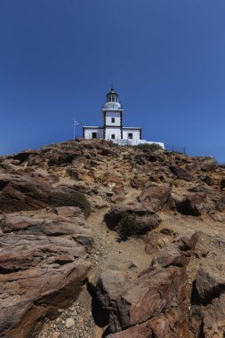 Santorini, Cape Akrotiri Deniz feneri, kayalıklarda duran beyaz bir deniz feneri. Arka planda güzel, masmavi bir gökyüzü