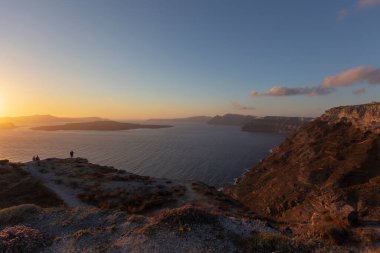 Caldera üzerinde Santorini gün batımı, sağ tarafta adanın kıyıları ve sol tarafta deniz ve batan güneş..