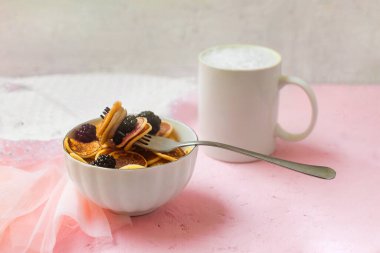 Üzerinde böğürtlen beyazı tabaklar olan mini krepler. Sosyal ağlarda yeni moda bir tatlı. Küçük Hollandalı poffertjes.