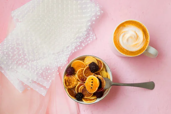 stock image Mini pancakes with blackberry white dishes on a pink table. A new trend dessert in social networks. Little Dutch poffertjes.