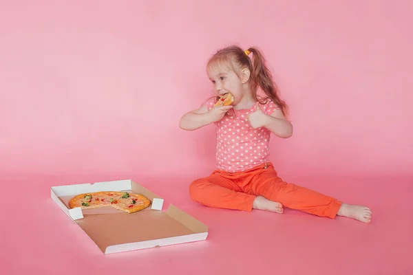 Pizza yiyen güzel küçük kız. Pembe arka plan. Boşluğu kopyala