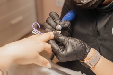 Kuaförde hırdavatçı manikürü. Manikürcü kadın parmaklarına manikür yapmak için elektrikli tırnak matkabı uyguluyor. Güzellik salonundaki donanım manikürünü yakından çek..