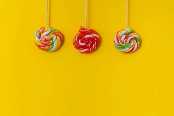 Sarı arka planda renkli bir lolipop. Lezzetli yuvarlak şeker