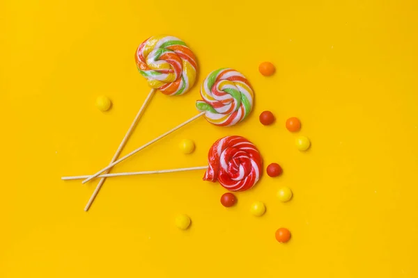 Sarı arka planda renkli bir lolipop. Lezzetli yuvarlak şeker