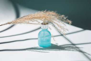 Mavi arka planda cilt bakım serumu. Güzellik ve evde bakım konsepti. Yüz derisi için vitamin. Gölge eğilimi