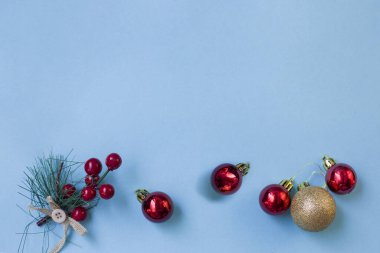 Noel kompozisyonu. Noel ağacının dallarından bir çerçeve, mavi arka planda kırmızı ve altın süslemeler. Düz şezlong, üst görünüm, boşluğu kopyala