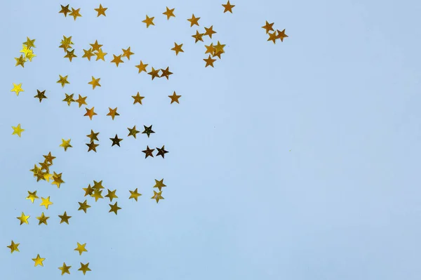 Small gold stars on a blue background. Copy spase