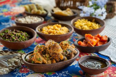 Gine tavuğu, kahverengi sosta kızartılmış ve yanında balkabağı, manyok, yeşil fasulye ve manyok unuyla birlikte bölgesel ürünler sunuluyor..