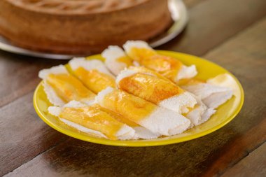 Masanın üzerinde erimiş peynirle birlikte sarı tabakta tapyoka. Brezilya gastronomisi.