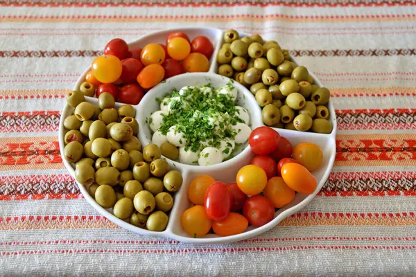 Masada duran domatesli, zeytinli ve mozarella peynirli bir tabak..