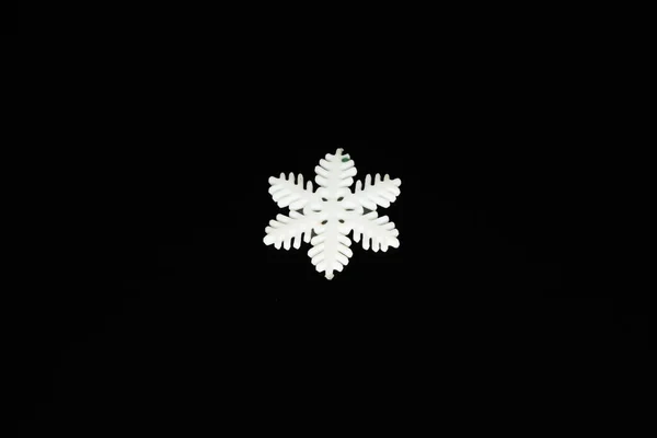 White plastic hexagonal snowflake on a black background — Stock Photo, Image