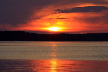 Batan güneşin sakin sulara yansıdığı manzara