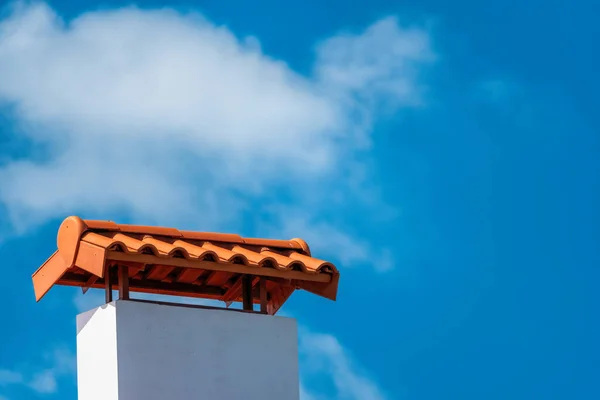 Brown tile roof under blue sky. The photo is divided on two part. One part is a roof made of clay tiles and the other is a blue sky. Brown surface of tile roof with natural color, texture and pattern.