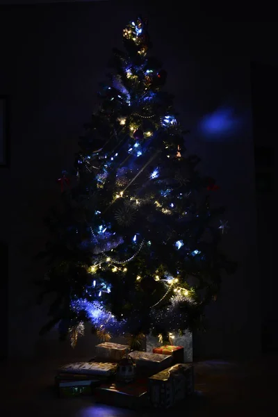 Mehrfachbeleuchteter Christbaum mit Öko-Spielzeug dekoriert Glühbirnen mit Geschenken darunter — Stockfoto