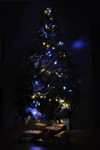 Ekolojik oyuncaklarla süslenmiş çok ışıklandırılmış Noel ağaçları altında hediyelerle parlayan ampuller