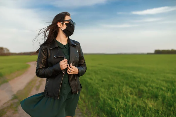 Uma rapariga com uma máscara médica corre ou caminha num campo verde. Verão de primavera de quarentena. coronavírus. COVID 19. Vírus da gripe, constipações — Fotografia de Stock