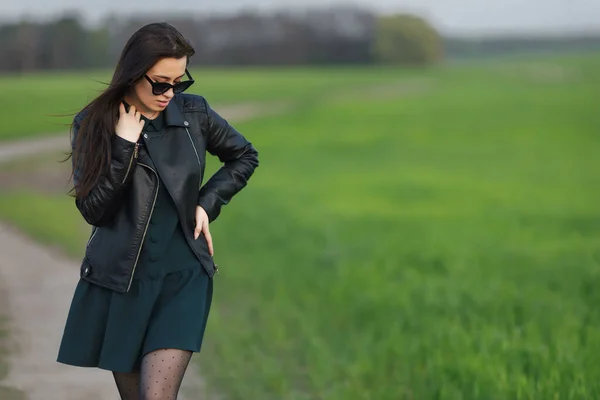 Portrait complet d'une fille élégante marchant le long d'un champ vert. Une jeune femme souriante marche dans la nature. Prairie printanière verte — Photo